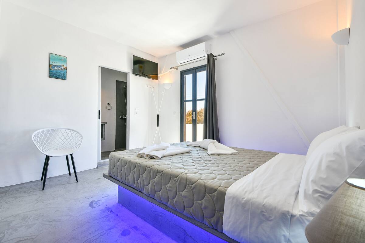 Un dormitorio moderno con cama, una silla y una ventana.