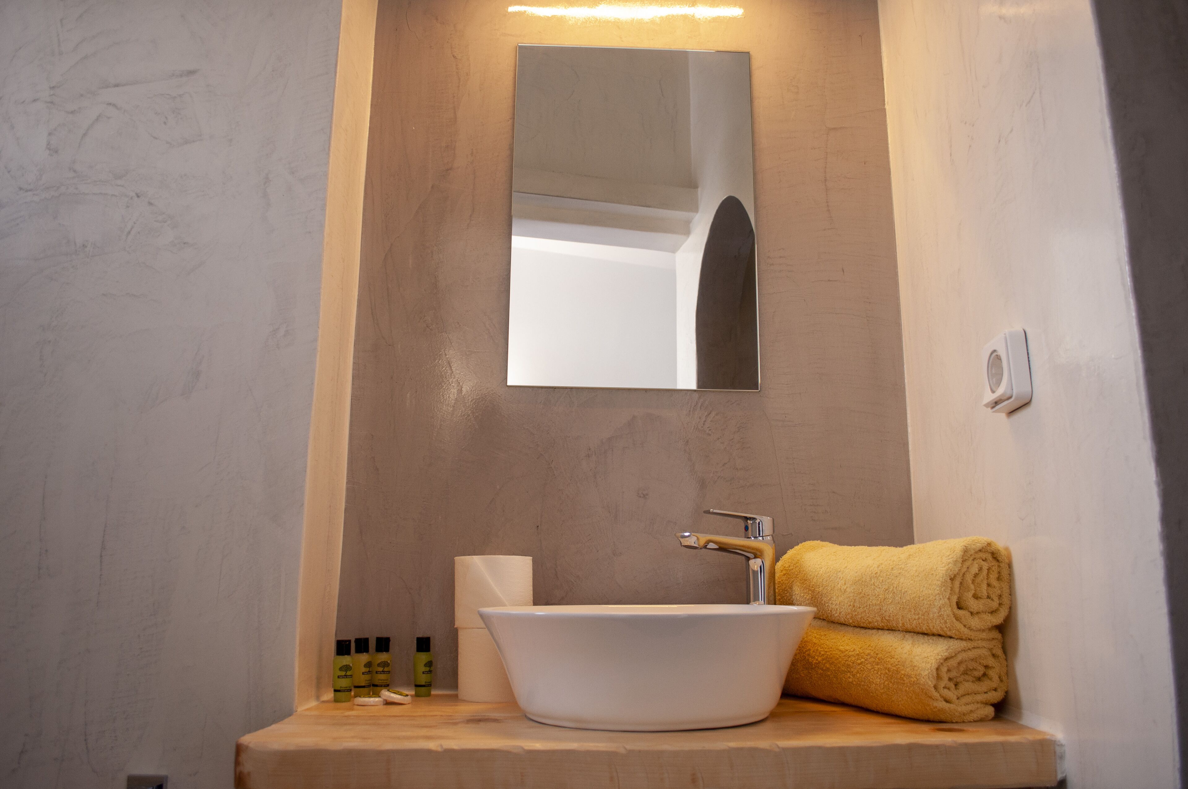 A bathroom with a white sink, a mirror, a towel, and toiletries.