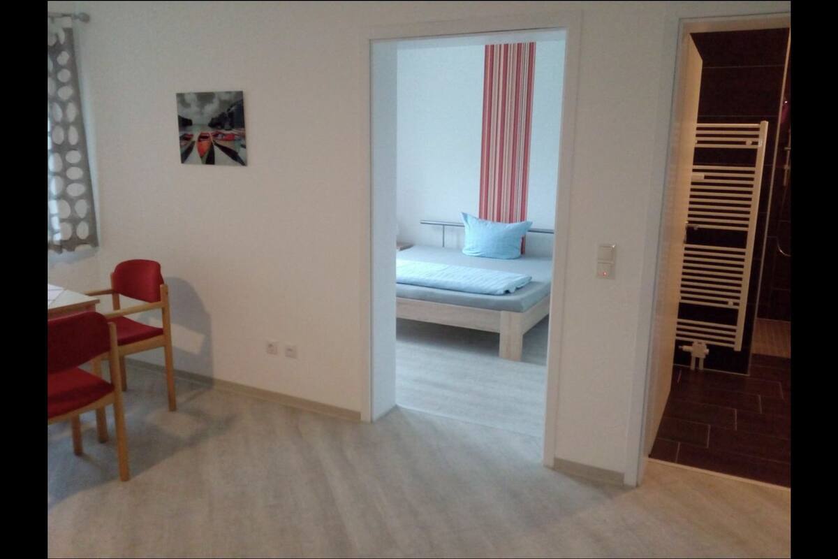 Une pièce comprenant un lit, une chaise, un bureau et un espace douche.