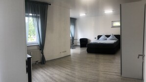 A bedroom with a bed, a chair, a radiator, and a window with curtains. - Appartemens Haus Maria Anna (Bad Ems)