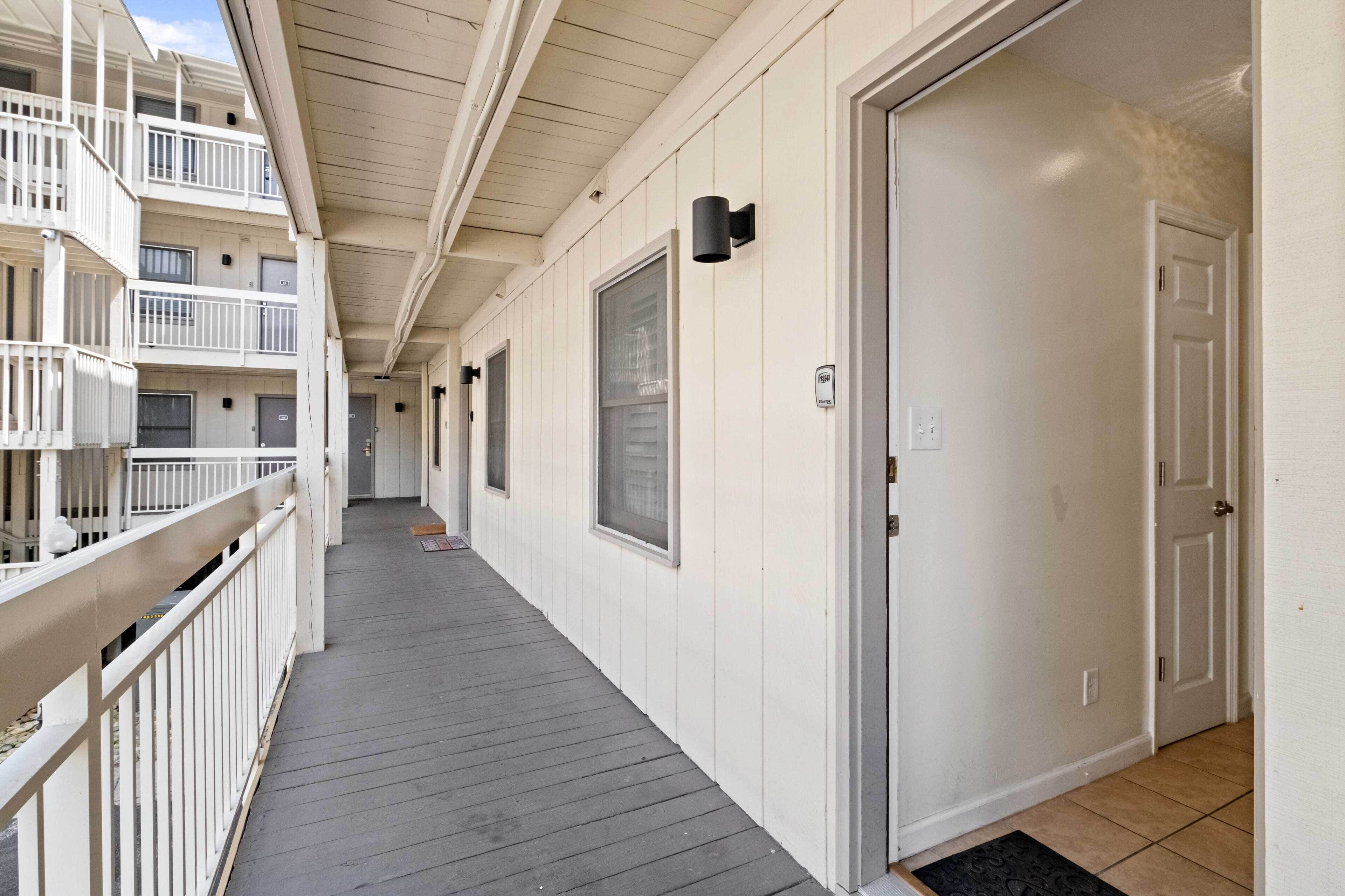 A corridor with a wooden deck, white walls, and a door on the right.