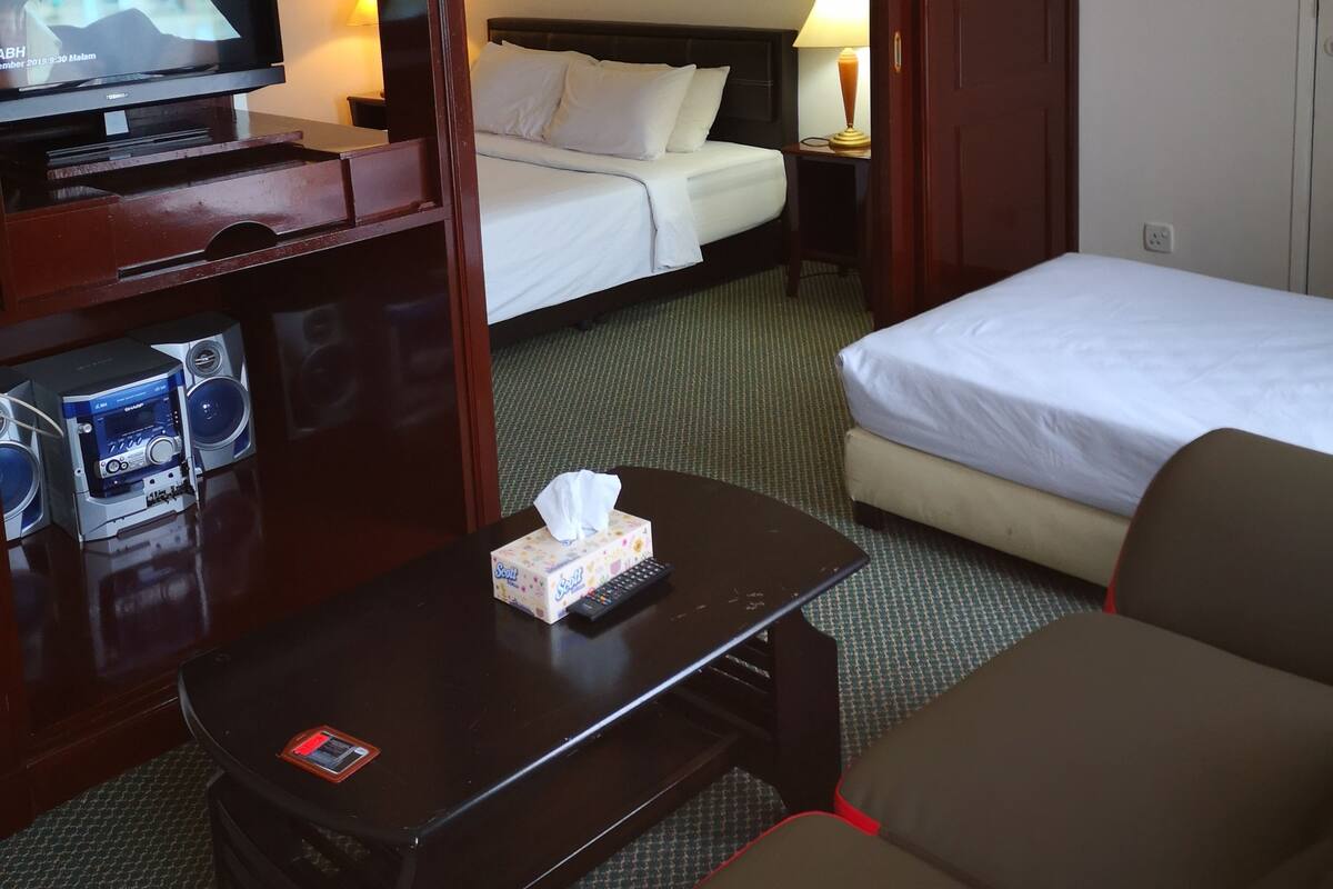 Une chambre d’hôtel comprenant un lit, un bureau avec une télévision, une table de chevet avec une boîte de mouchoirs et une chaise.