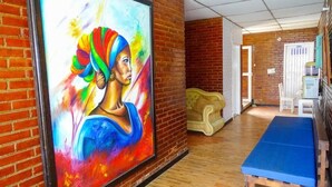 A room with a large painting on the wall, a wooden bench, and a door in the background. - Hotel La Gran Mansion De La Negra (Melgar)