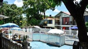 A swimming pool with a white fence, surrounded by trees and buildings. - Hotel La Gran Mansion De La Negra (Melgar)