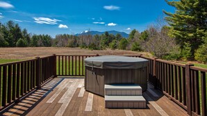 Un bain à remous sur une terrasse en bois avec vue sur les montagnes.