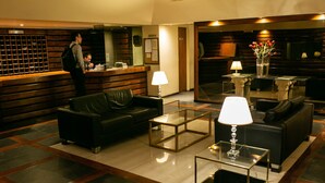 A lobby with a reception desk, leather sofas, glass coffee tables, and a vase with flowers. - Santa Fe by BA Tango Apartments (Buenos Aires)