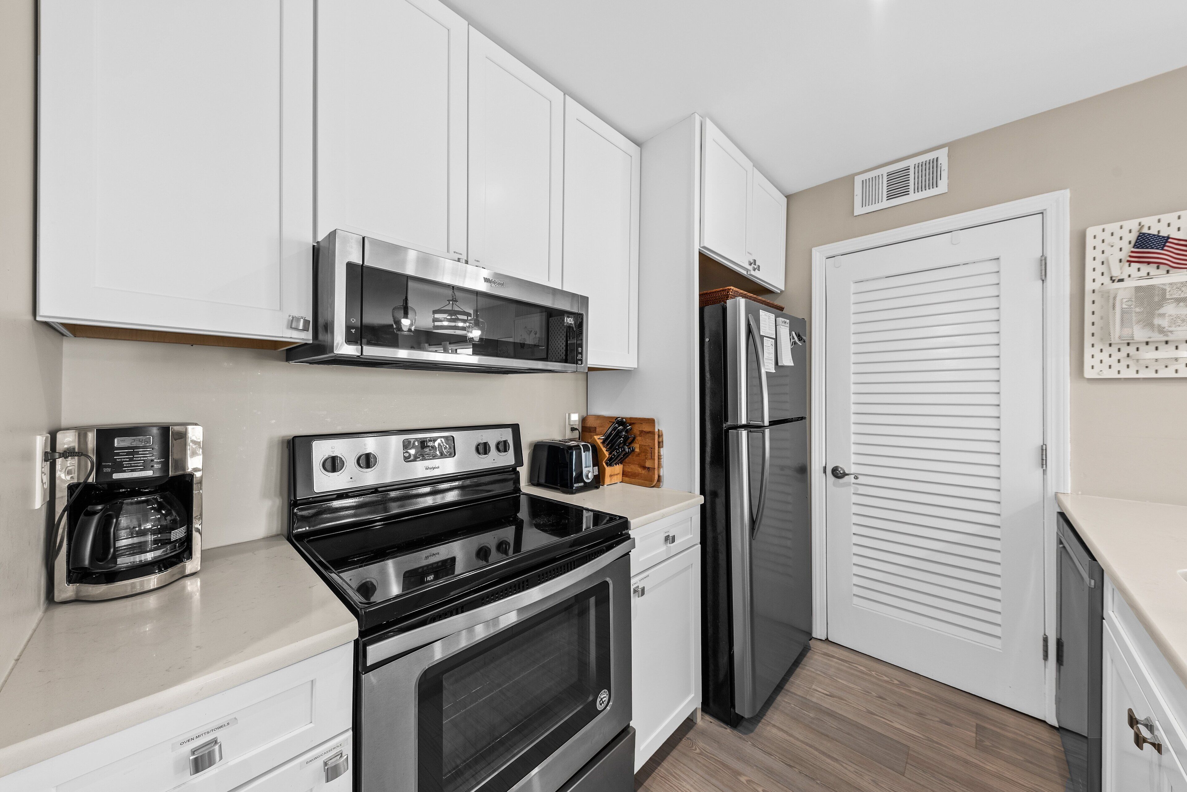 A kitchen with white cabinets, a stainless steel range, a coffee maker, and a refrigerator.
