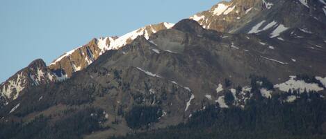 A mountain range with snow-capped peaks and dense forested areas.