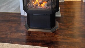 A wood-burning stove in a room with a tiled shower area and a trash can. - Charming Cottage in Fabulous Location in Niagara on the Lake (Niagara-on-the-Lake)