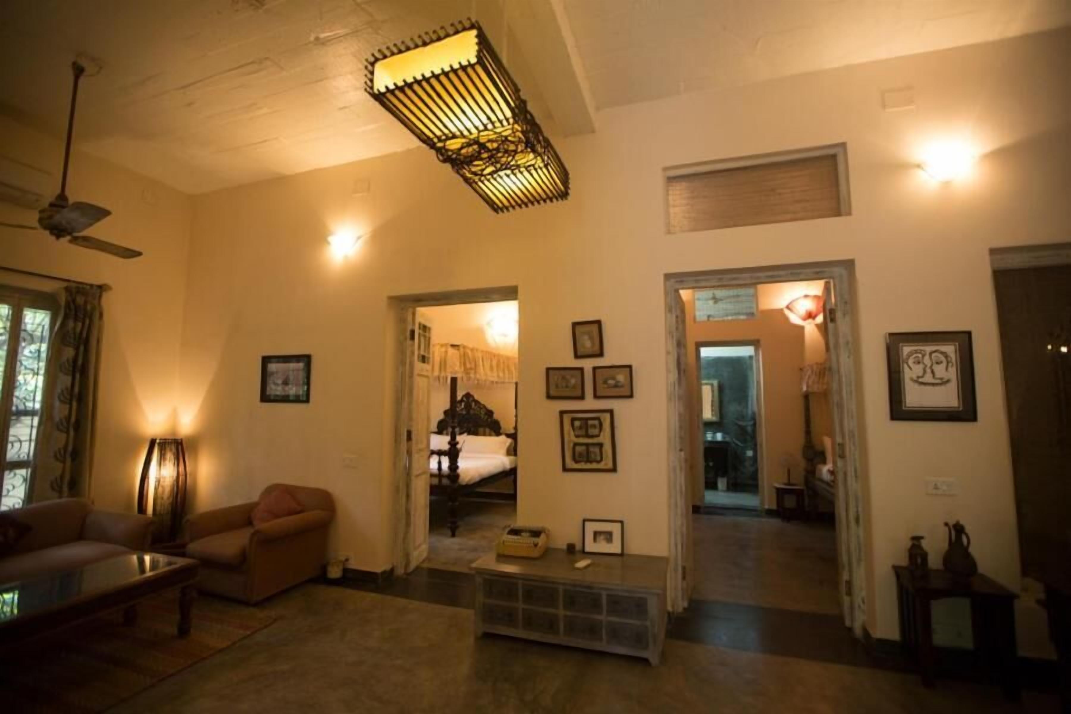 Ein gemütliches Wohnzimmer mit Sofa, Couchtisch und Lampe. Ein Flur führt zu einem weiteren Zimmer mit einem Bett.
