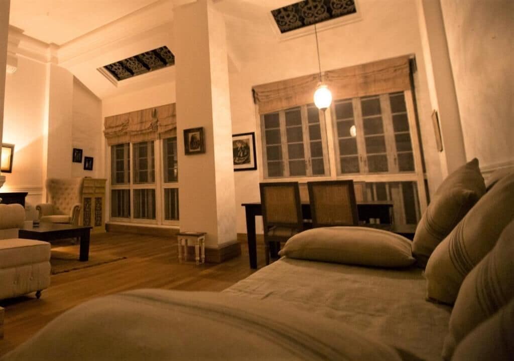 A room with a bed, a sofa, a small table, and a window with curtains.