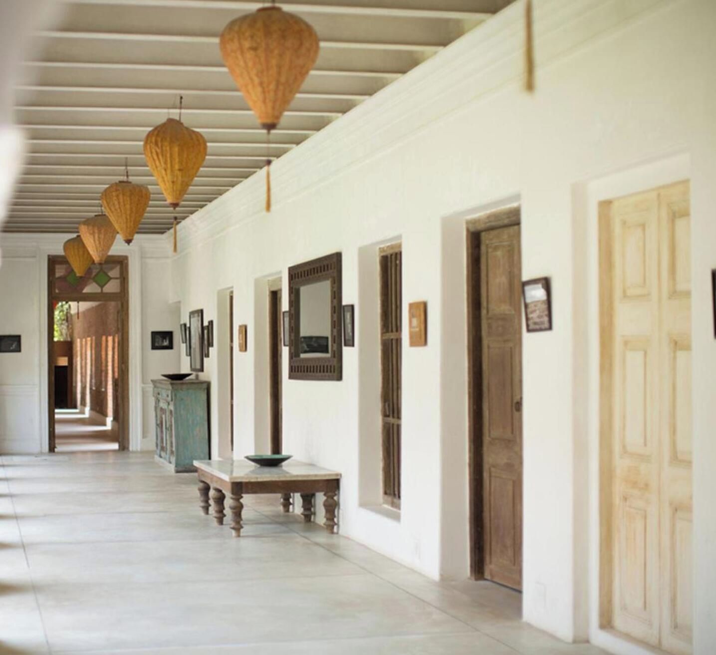 A hallway with doors, a bench, and hanging lanterns.