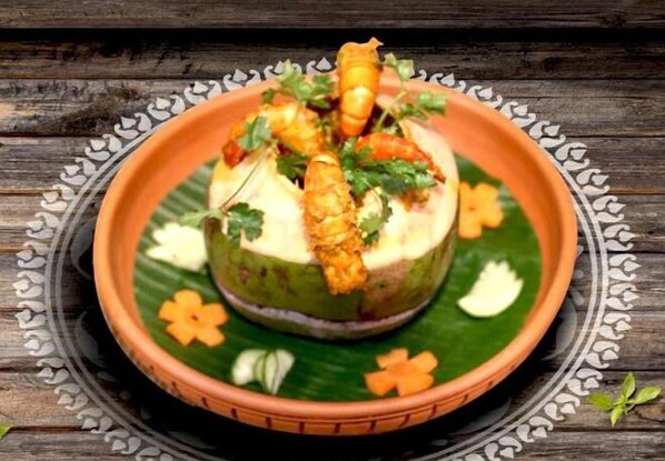 Plato con mariscos y hierbas sobre una hoja de plátano, servido en un plato estampado.