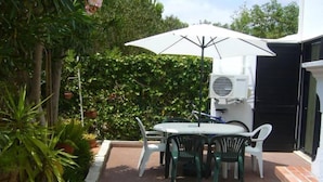 A patio with a table and chairs, an umbrella, and an air conditioning unit. - Beautiful Townhouse for golfers and beach holidays in sunny Vilamoura (Vilamoura)
