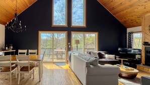 A spacious living room with a high ceiling, a large sofa, a TV, and a fireplace.