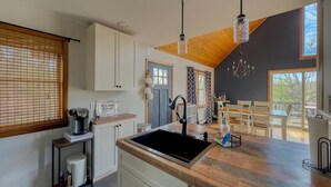 A kitchen with a sink, cabinets, a coffee maker, and a welcome sign.