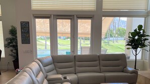 Een moderne woonkamer met een grote hoekbank, een houten salontafel en een plafondventilator.