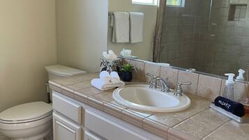 A bathroom with a toilet, sink, and mirror. There are towels and toiletries on the counter.