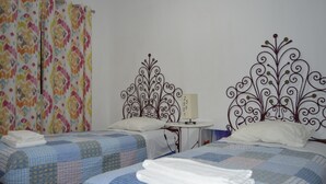 A hotel room with two beds, floral curtains, and decorative metal headboards.