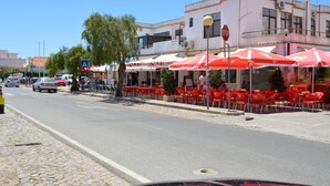 A street with outdoor seating and a building with multiple floors.