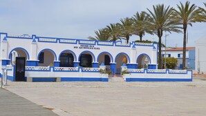A building with a white and blue facade, featuring arched doorways and a sign indicating it is a tourist information center.