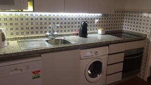 A kitchen with a sink, a coffee maker, a washing machine, and a microwave.