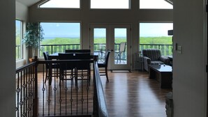 A spacious balcony with a view of the landscape, a ceiling fan, and a dining area with chairs and a table. - Scenic Lakeside Chateau with Heated Pool, Hot Tub & Outdoor Kitchen-TV-Fireplace (Belle)