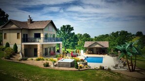 A two-story house with a swimming pool, a hot tub, and a covered patio area. - Scenic Lakeside Chateau with Heated Pool, Hot Tub & Outdoor Kitchen-TV-Fireplace (Belle)