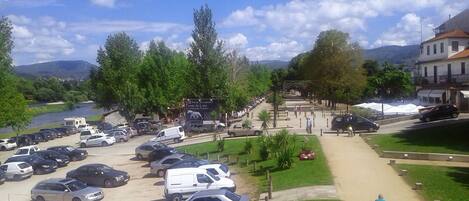 A parking lot with several cars and a white van. There is a signboard and a pathway leading to a building.