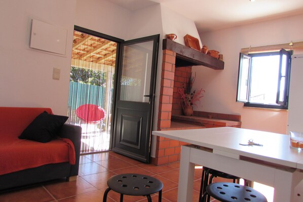 A living room with a red sofa, a white table, and a black stool. There is a sliding glass door leading to a balcony. - Local tourism - Casas da Nazare - Ponte de Lima (Ponte de Lima)