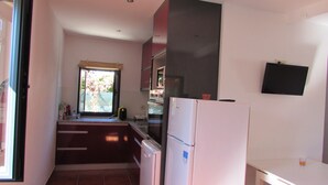Cocina compacta con refrigerador, horno y ventana.