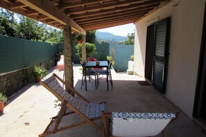 A covered patio with a table and chairs, a rocking chair, and potted plants. - Local tourism - Casas da Nazare - Ponte de Lima (Ponte de Lima)