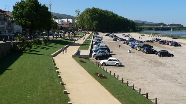 Un aparcamiento junto a la playa, con un camino que lleva a un edificio de techo rojo.