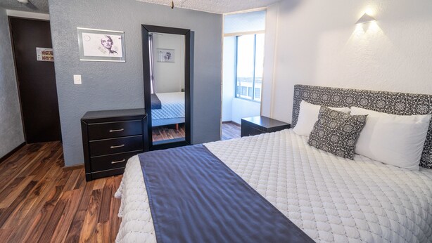 Un dormitorio con cama, cómoda, espejo y ventana.