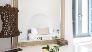 Un dormitorio con cama, mesita de noche, espejo y ventana.