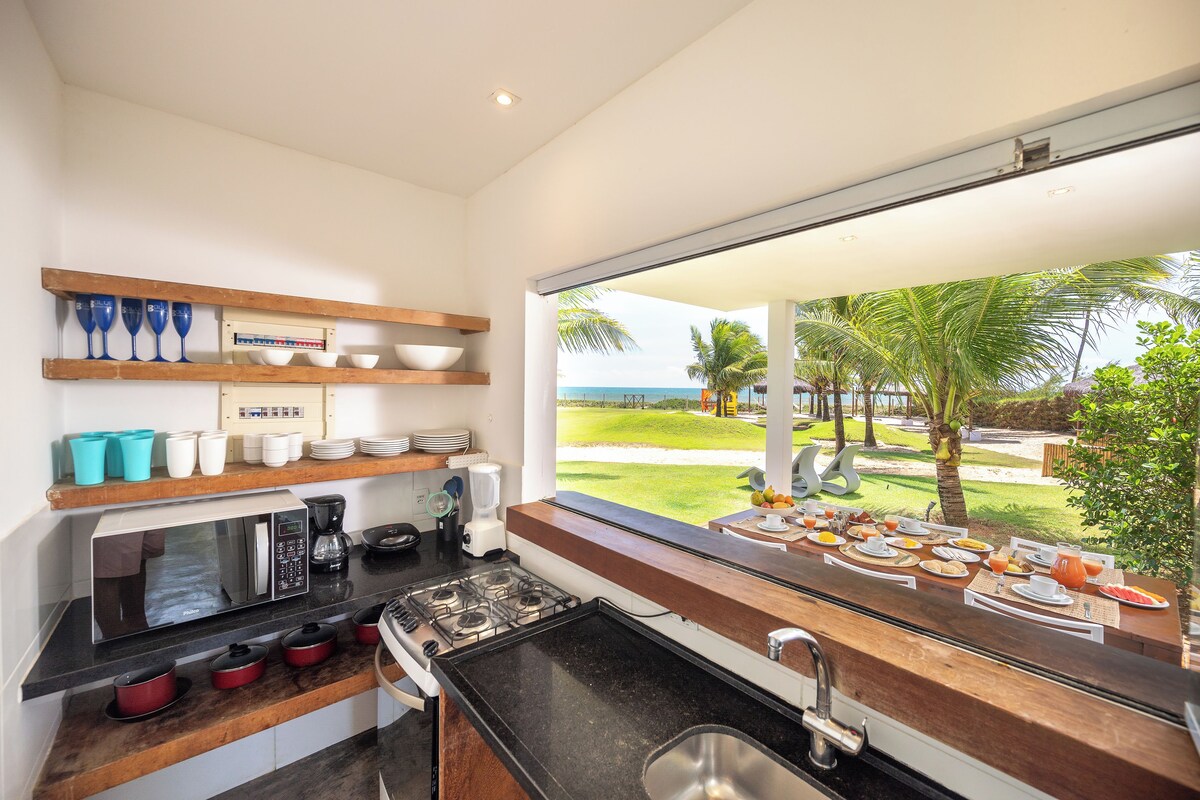A modern kitchen with a large window, a microwave, stove, and various kitchenware.