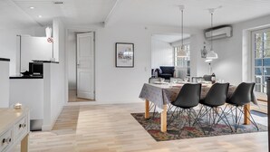 A modern dining area with a table set for four, a patterned rug, and a view of the outside through large windows. - 5 bedroom beautiful home in Otterup (Otterup)