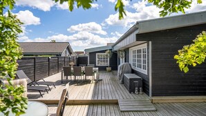 A wooden deck with outdoor furniture, a barbecue grill, and a window overlooking a backyard. - 5 bedroom beautiful home in Otterup (Otterup)