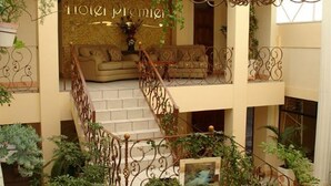 Um hall de hotel com escadas, um sofá e plantas decorativas.