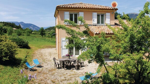Une maison à deux étages, avec un toit recouvert de tuiles, une antenne parabolique et une allée gravillonnée.