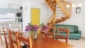 Une cuisine moderne avec des meubles blancs, une porte jaune et un escalier en bois.