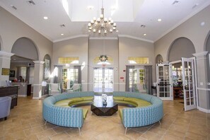 A spacious lobby with a circular seating area, a chandelier, and a reception desk.