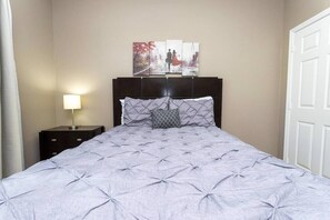 A bedroom with a bed, a nightstand, a lamp, and a wall-mounted artwork.