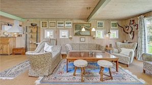 En hyggelig stue med træloft, stribede sofaer, et træbord og et gulvtæppe.
