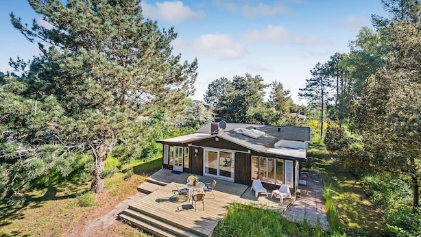 Et moderne hus med en terrasse, store vinduer og en parabol.