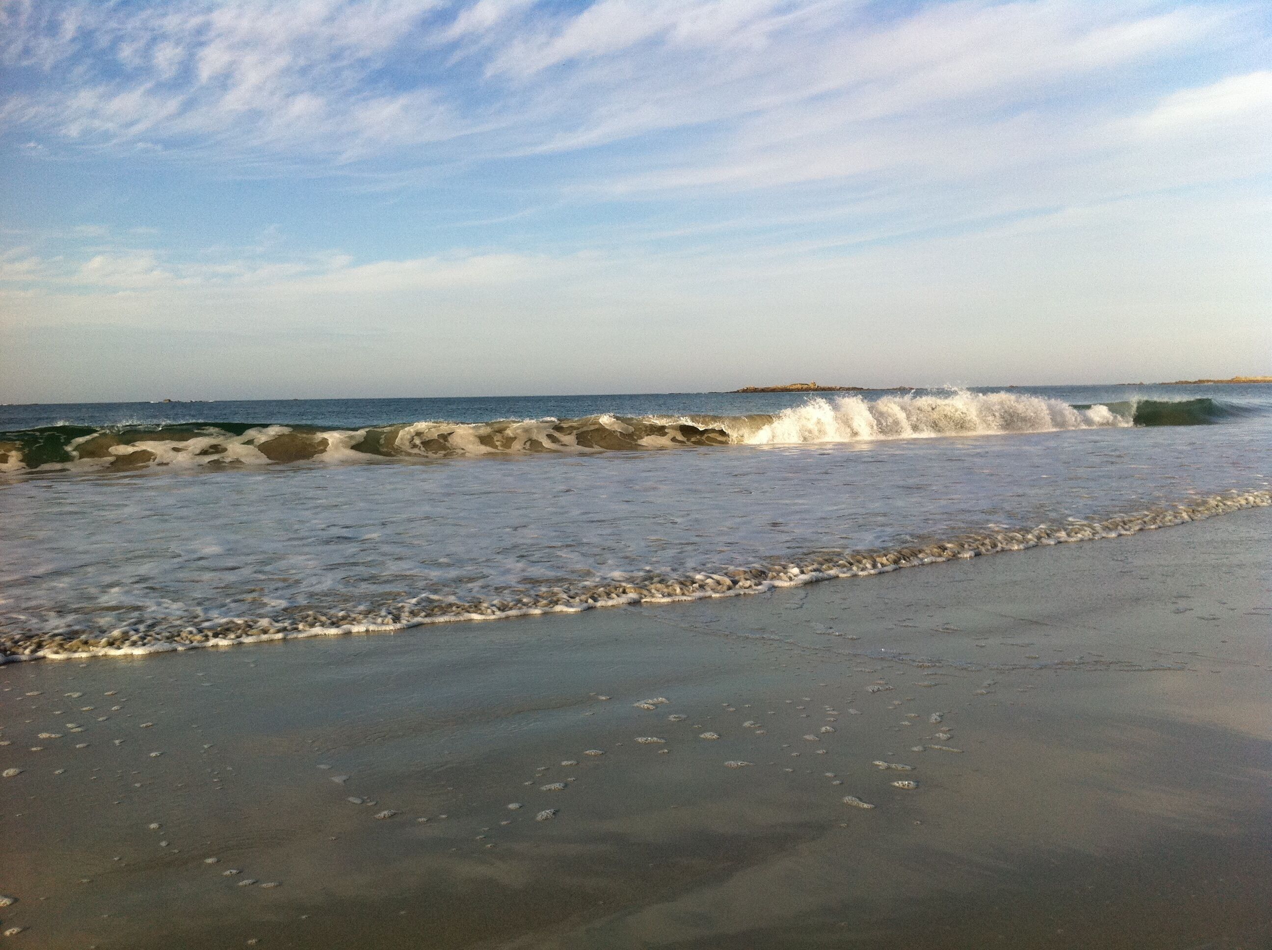 Una playa con olas rompiendo en la orilla y un cielo despejado.