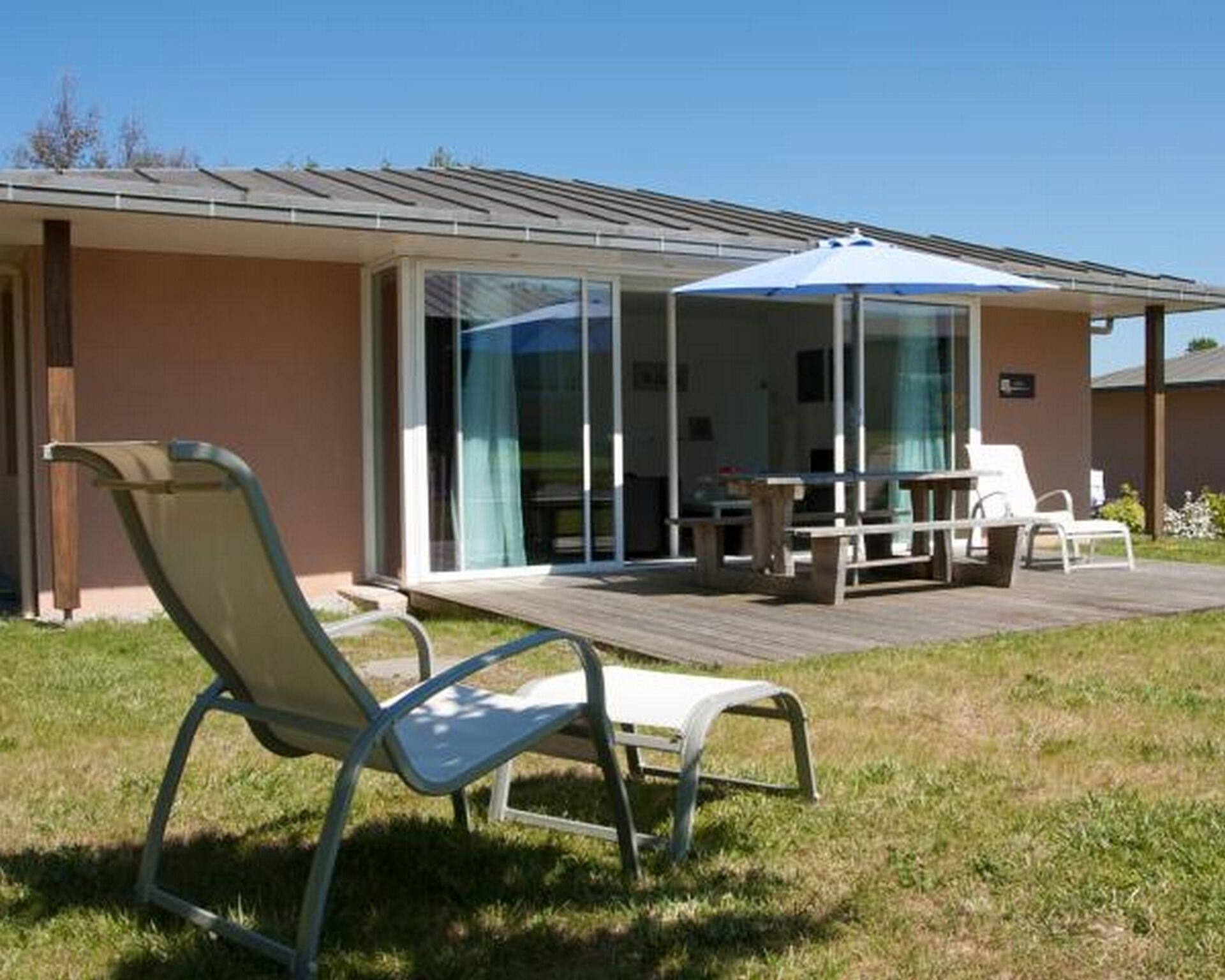 Una casa moderna con un patio, dotato di tavolo e sedie, una zona relax coperta e una porta in vetro che dà su un terrazzo.