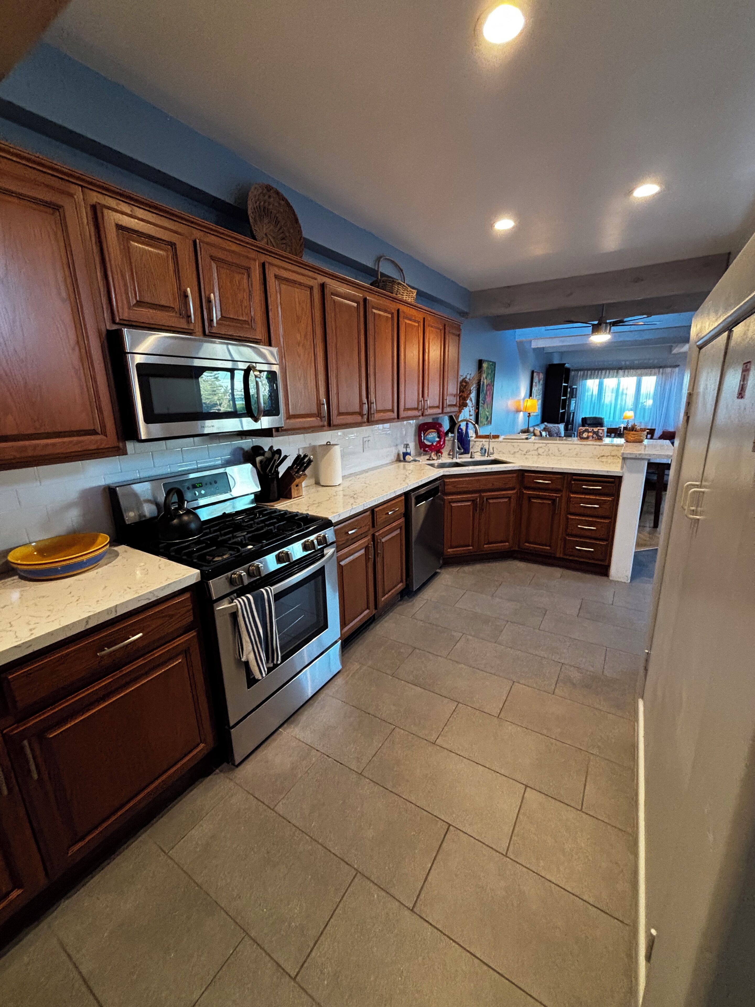 A kitchen with wooden cabinets, stainless steel appliances, and a tiled floor.