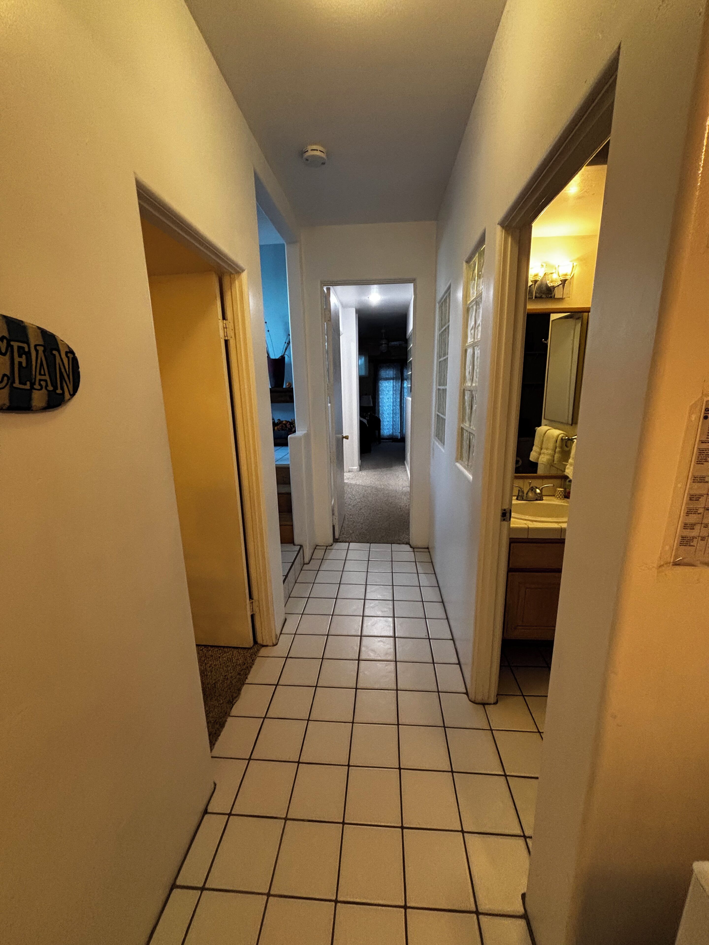 A hallway with tiled flooring, a door labeled "OCEAN", and a bathroom visible to the right.