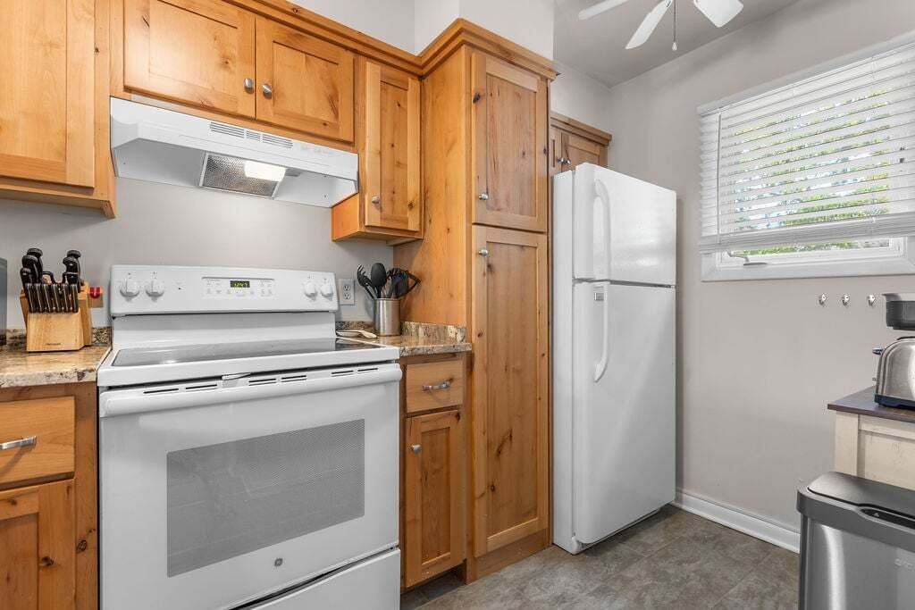 A kitchen with wooden cabinets, a white stove, and a refrigerator.